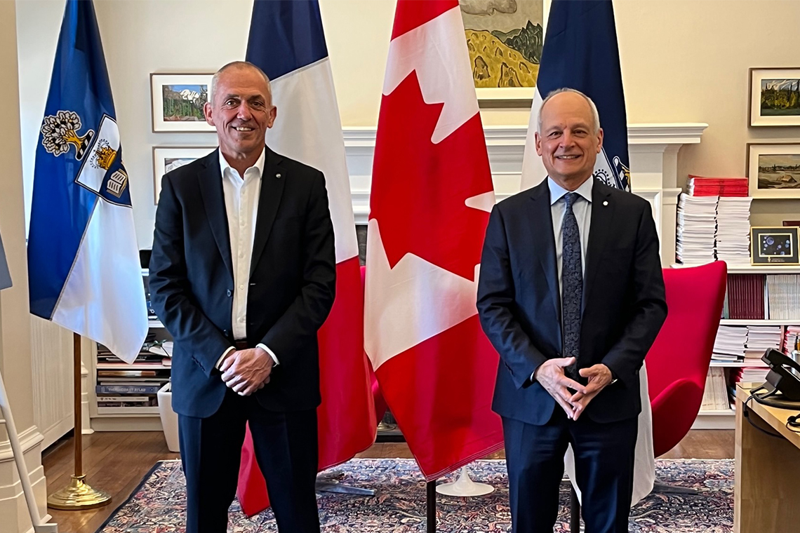 Antoine Petite, CEO of CNRS, and U of T President Meric Gertler standing in front of flags