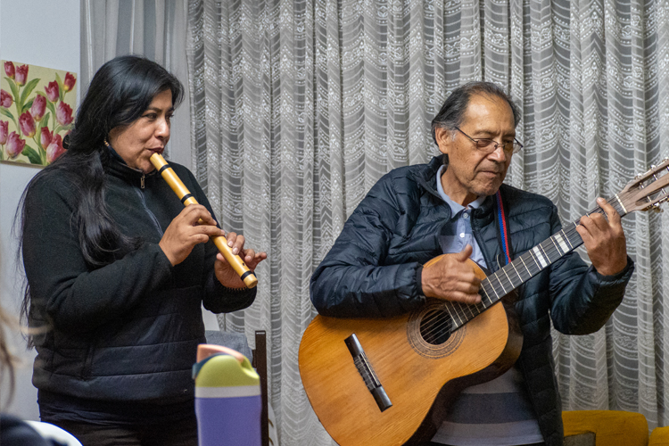 Two people, one playing a guitar and the other playing a flute.