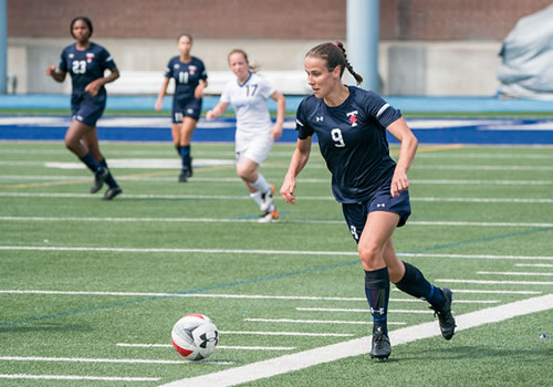 Natasha Klasios about to kick a ball on the soccer field