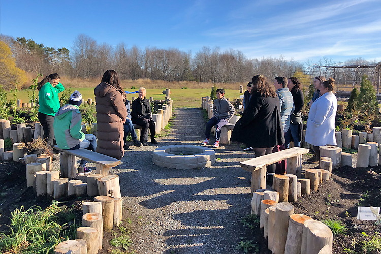 A group of students and teachers sitting outdoors at a residential school site