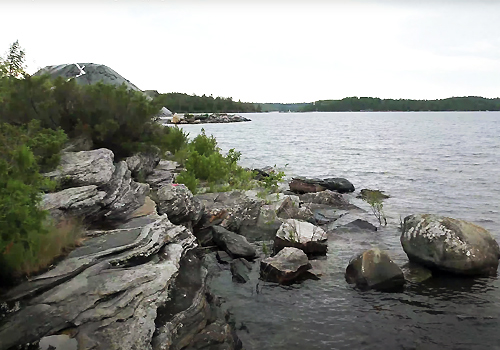 A lake surrounded by a rocky landscape on a grey day.