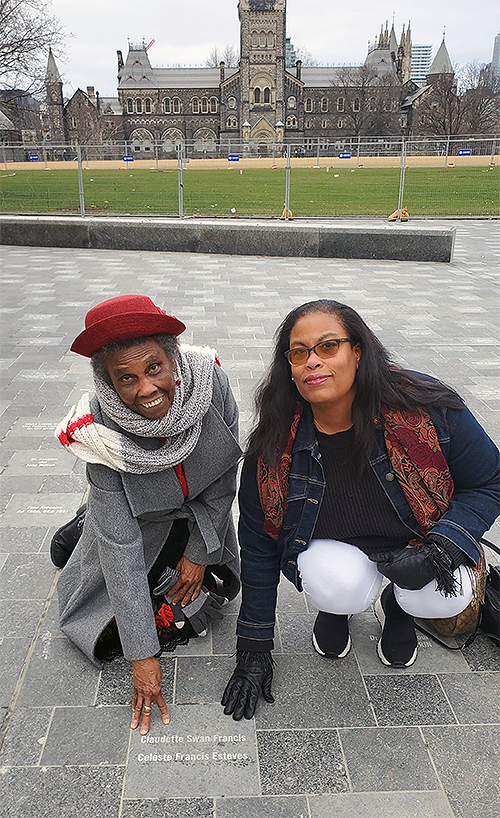 Claudette Francis and Celeste Francis Esteves outside convocation hall touching their paver stone.