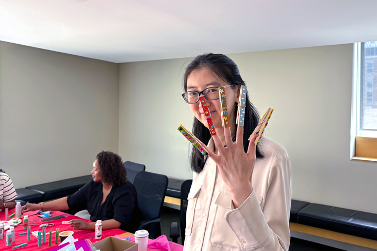 A person with colourful clothing pins clipped to the ends of their fingers.