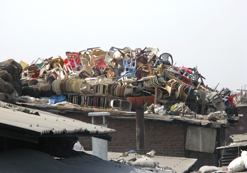 A pile of plastic chairs and other waste at a recycling facility