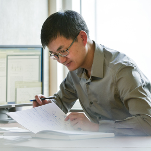 A person looking at paperwork beside a computer.