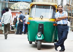 A man standing in front of his tuk-tuk in India.