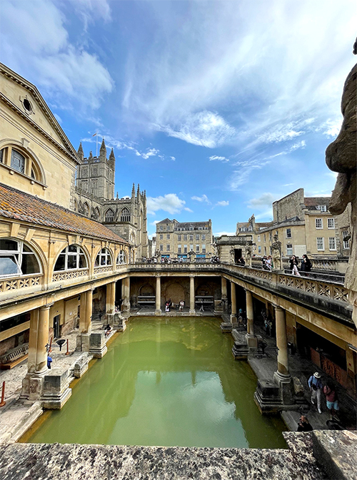 Large old buildings with a green pond in the middle.