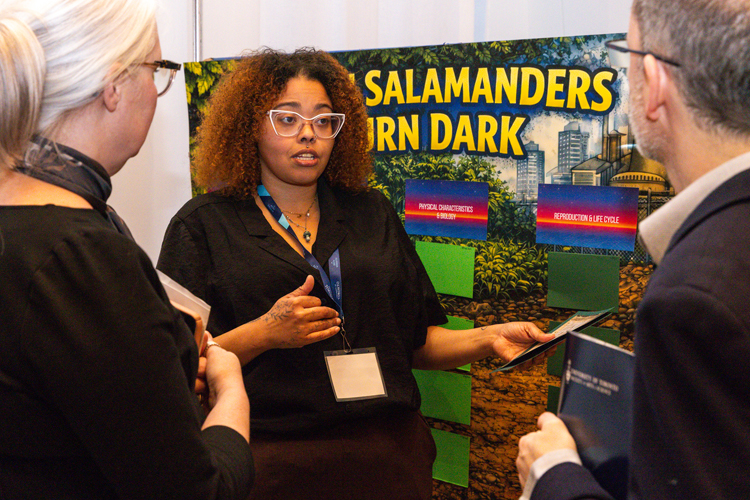 Montana McIntosh in front of her poster with two people engaged in conversation 