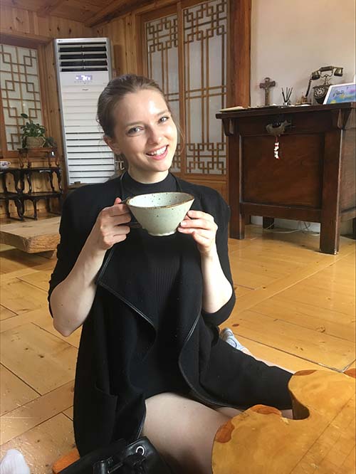 Samantha Pierre sitting on a floor holding a teacup.