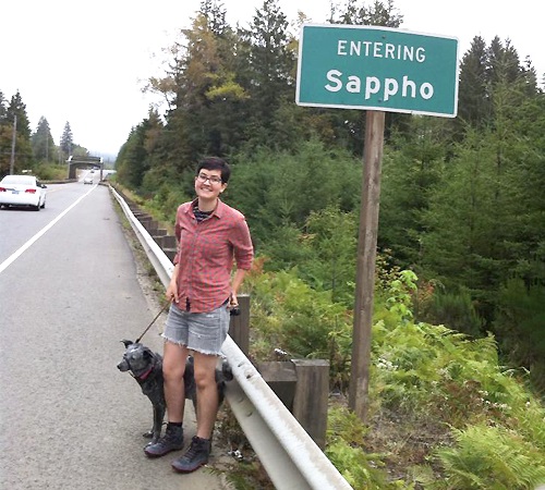 Sarah Dowling in front of a roadsign saying Entering Sappho
