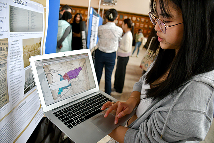 Sarah Chen standing with their laptop showing a picture of a map.