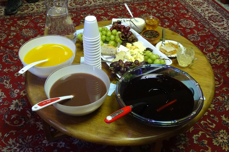 A table laden with bowls of sauces, fruit and cheese