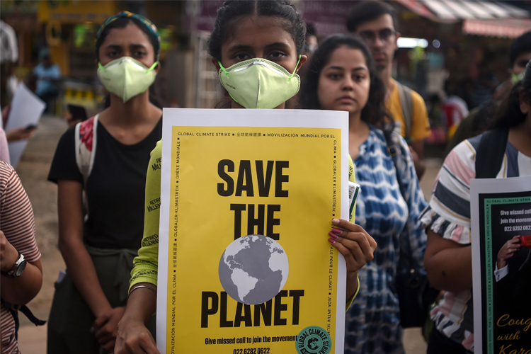 A person holding a yellow sign that says "save the planet."