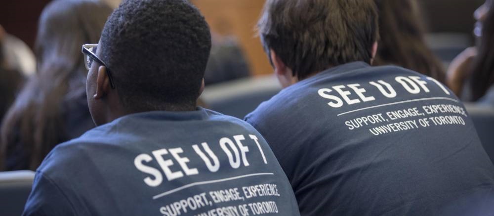 Two men - shot from the back - wearing See U of T t-shirts