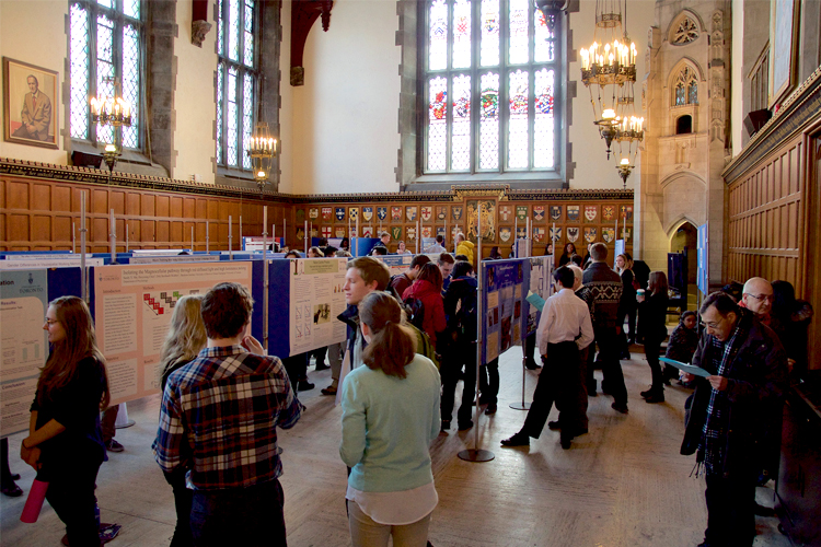 Dozens of students the Great Hall at Hart House with research presentation.