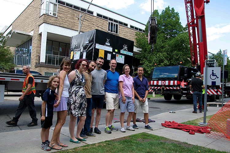 Smiling members of the Psychology department and their families in front of a truck and crane during the delivery of the MRI machine.