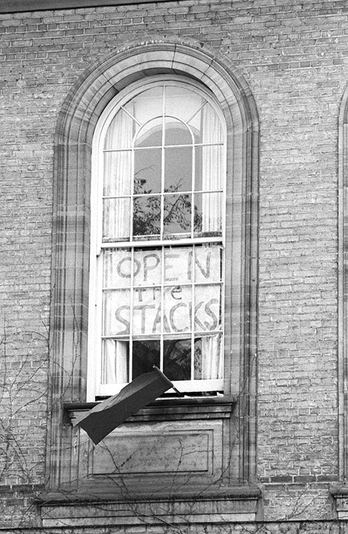 U of T window with posters that read Open the Stacks.
