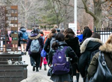 A group of students walk down a busy street at St. George campus.