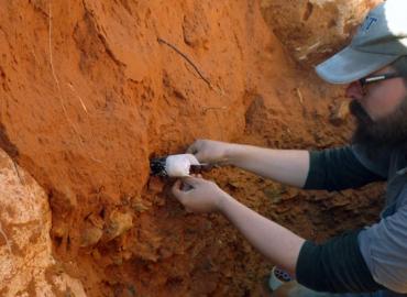 Steven James Walker extracts a sample from red sand.