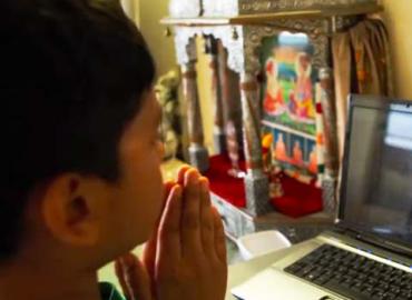 boy looking at computer screen while praying