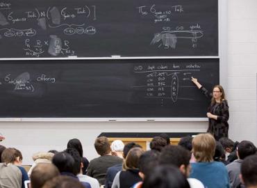 Diane Horton lecturing while pointing at notes on a chalkboard.