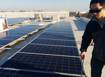 Cheng Lu standing by a series of solar panels at a solar farm.