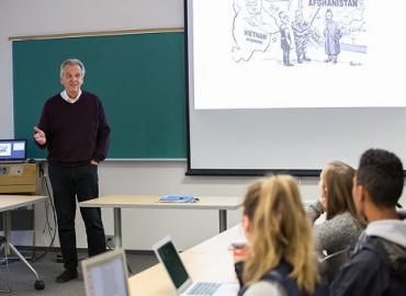 Professor Ronald Pruessen standing at the front of a classroom 