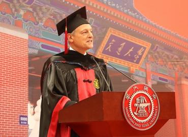 Meric Gertler speaking at a podium wearing a cap and gown