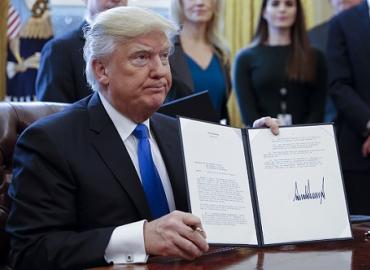 President Trump holding up an executive order with his signature on it