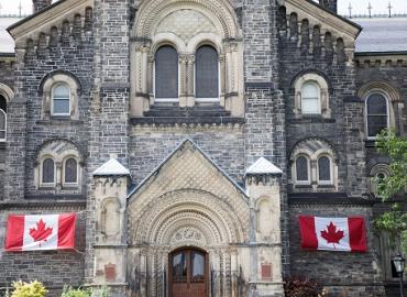 Canadian flags flank the entrance of University College at U of T. 