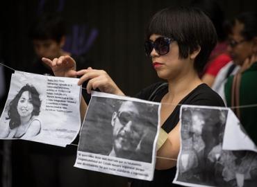 A woman places banners during a protest of the July 2015 murder of journalist Rubén Espinosa, government critic Nadia Vera and two other women in Mexico City.