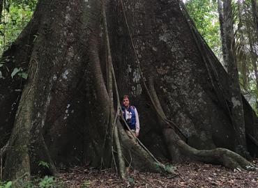 Kerry Bowman standing in front of a huge tree in the Amazon
