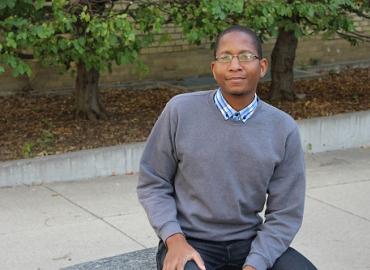 Vincent Tembo sitting on a stone bench on the U of T campus.