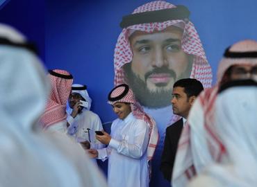 Young Saudis chat by a poster of Saudi Crown Prince Mohammed bin Salman during a tech forum in Riyadh this month. 