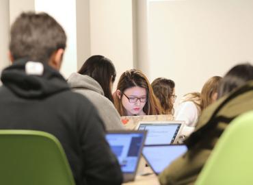 Juliana Lee, studying in a classroom, looking at a laptop.