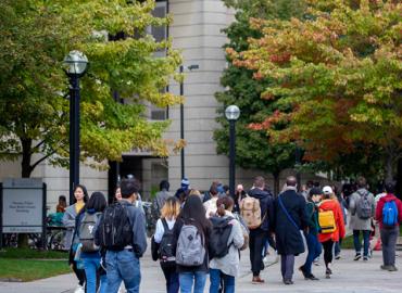 A large group of students walking on the sidewalk besides Robarts Library.