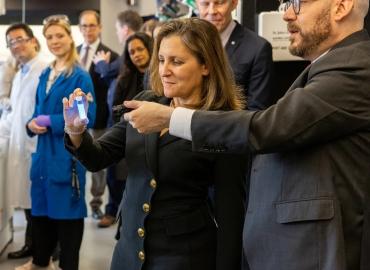 Alán Aspuru-Guzik (right) and Deputy Prime Minister Chrystia Freeland holding a glowing blue vial.