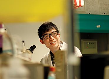 A male student in a research lab with microscope 
