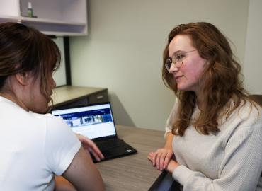 Two women at a desk looking over a computer