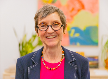 Antoinette Handley smiles in front of a colourful painting
