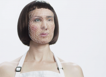 Graphic of a &amp;quot;robotic&amp;quot; woman with short brown hair, blue and green eyes, and a geometric design across her face.