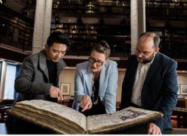 3 Old Books New Science lab investigators examining a large medieval manuscript