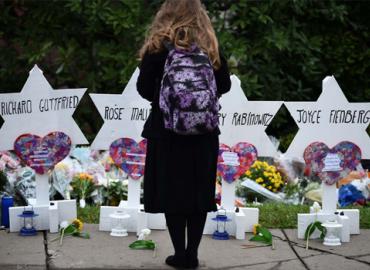 A woman stands in front of a makeshift memorial located outside of the Tree of Life synagogue in Pittsburgh.
