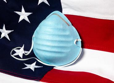 Image of a U.S. flag and a face mask.