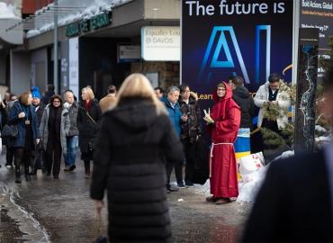 A group of people walking down a street beside a man wearing a red robe.