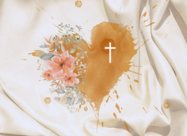 A heart painted on fabric with flowers on one side and a cross on the other