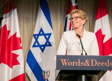 Ontario premier Kathleen Wynne speaking from a podium at Words &amp;amp; Deeds Award dinner.