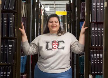 Kaitlyn Ferreira standing between two bookshelves in a library