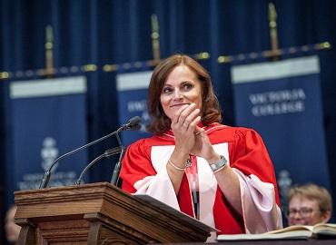 Judy Goldring clapping behind a podium at Convocation 2019