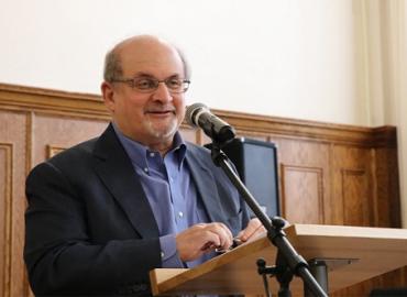 Salman Rushdie speaking at a microphone